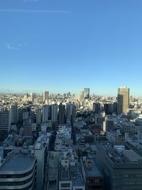 Aerial view of buildings in city against clear blue sky