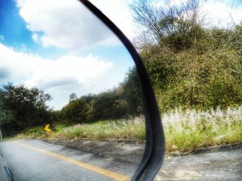Road seen through side-view mirror of car