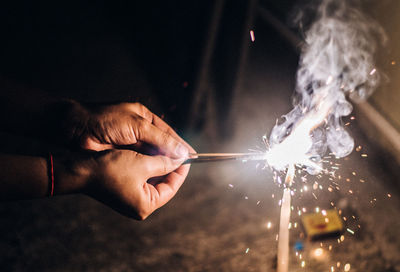 Close-up of hand holding sparkler at night