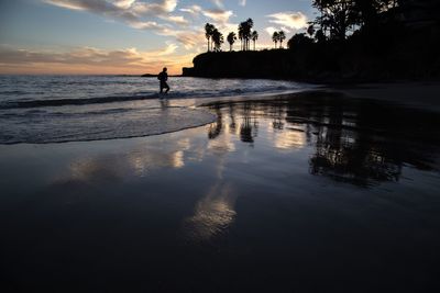 Silhouette man at beach against sky during sunset