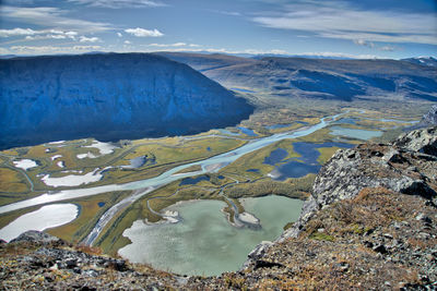 Aerial view of river by mountains against sky