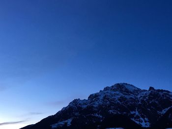 Low angle view of snowcapped mountains against clear blue sky at dusk