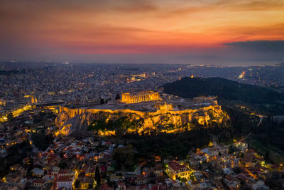 Illuminated cityscape against sky during sunset