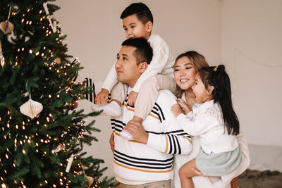 An asian multi-racial family with two children celebrate the christmas holiday in a decorated house