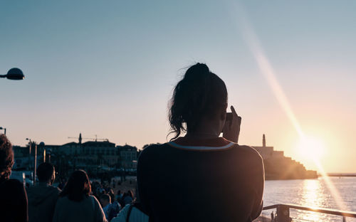 Rear view of people in city against sky during sunset