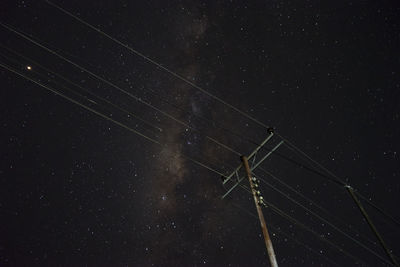 Low angle view of electricity pylon against sky at night