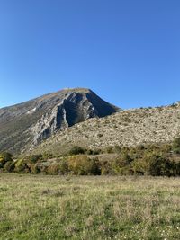 Scenic view of field against clear blue sky  and mountains