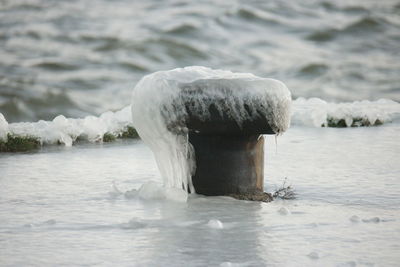 Bollard over frozen pier on lake