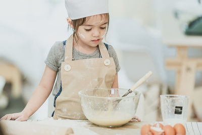 Girl holding ice cream in bowl at kitchen