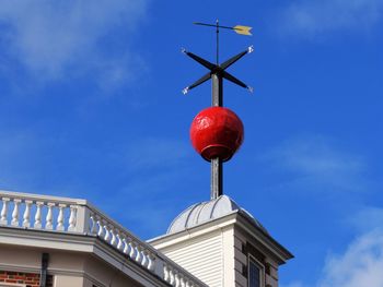 Low angle view of weather vane on top of building against blue sky