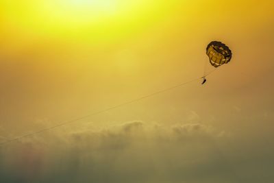 Low angle view of person paragliding against sky during sunset