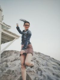 Low angle view of woman running on sand heap against sky