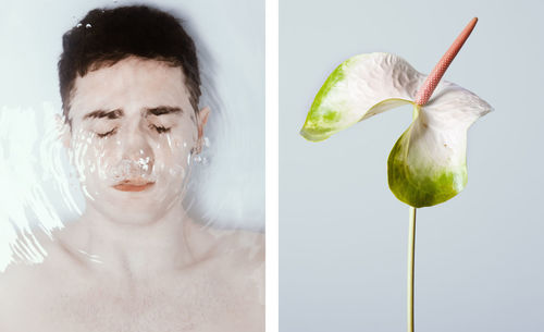 Close-up portrait of young man eating fruit against white background