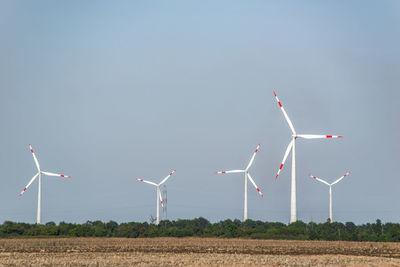 Wind turbines on field against sky