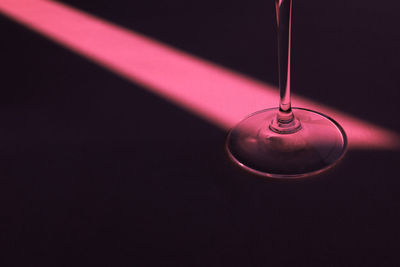 Stylish pink spotlight and wineglass on the table.