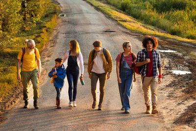 Rear view of friends walking on road