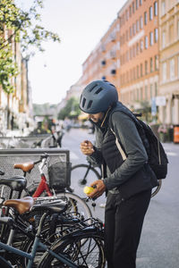 Businessman talking on smart phone while standing near bicycle at parking station