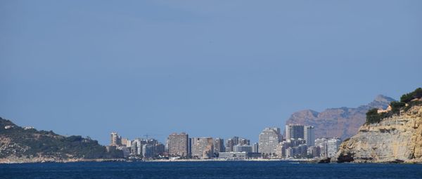 Sea by buildings against clear blue sky