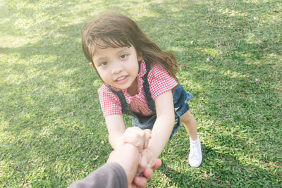 Portrait of girl holding hand of father on grass