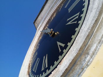 Low angle view of airplane against clear blue sky