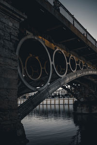 Arch bridge over river in city against sky