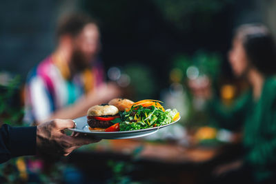 Cropped hand serving food to couple at restaurant