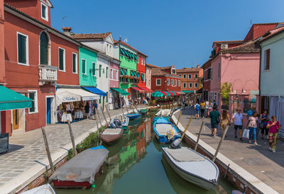 Boats moored in canal by buildings in city against sky