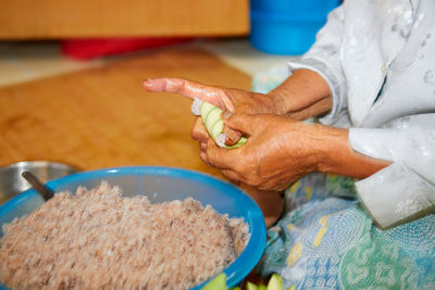 Hands of senior woman wrapping the sticky rice with palm leaf or ketupat palas