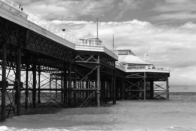 Buildings by sea against cloudy sky