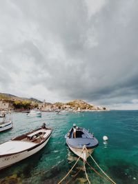 Sailboats moored on sea against sky