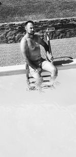 Portrait of shirtless man sitting in swimming pool