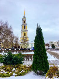 Trees and buildings against sky during winter