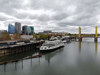 Boats in river by buildings in city against sky