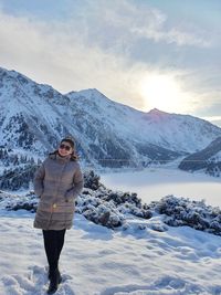 Woman standing on snowcapped mountain against sky