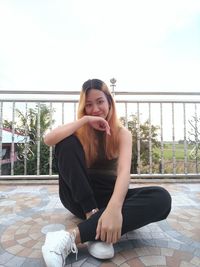 Portrait of young woman sitting on railing