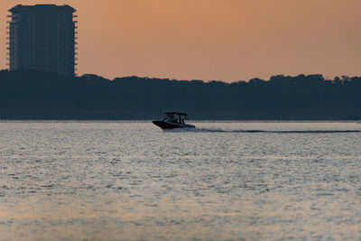 Boat sailing in sea against sky during sunset