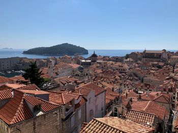 Aerial view of townscape by sea against clear sky