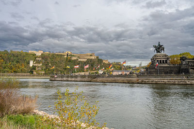 Buildings at waterfront against cloudy sky