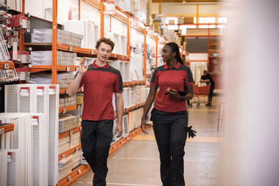 Male and female sales staff talking while walking in hardware store