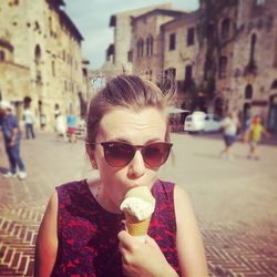 Close-up of young woman eating gelato ice cream on footpath