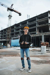 Full length portrait of young man standing at construction site