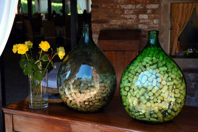 Corks in drop shaped glasses on a wooden table with yellow roses in a vase in torcello