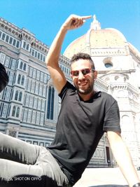 Portrait of smiling young man against building in city