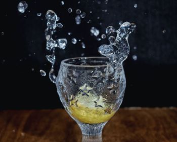 Close-up of water splashing on glass against black background