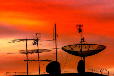 Silhouette of man using mobile phone against orange sky