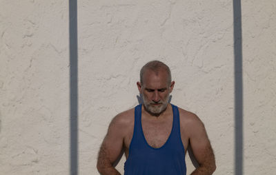 Portrait of adult man against white wall with shadow in summer