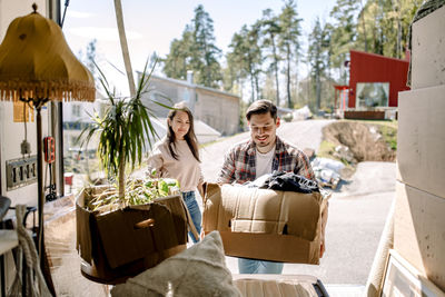 Couple picking cardboard boxes from delivery truck on sunny day