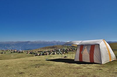 Tent on field against clear blue sky