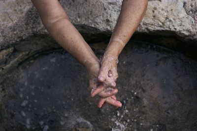 High angle view of man hand on rock