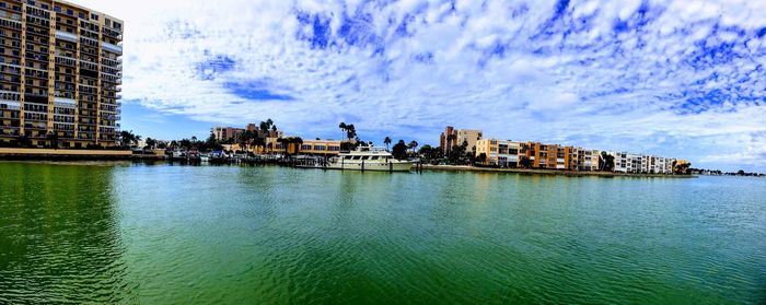 Panoramic view of buildings by river against cloudy sky